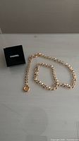 Chanel gold curb chain laid out beside branded box