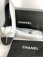 Pair of Chanel ballet flats on box with dust bag visible