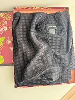 Scarf folded in floral box showing textured ribbed pattern and brand label