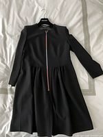 Full view of black dress on hanger displaying overall design and length