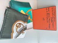 Two folded Hermès silk scarves beside orange box showing colourways and motifs