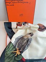 Scarf draped over Hermès box showing falcon illustration and box handwriting
