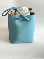 Front view of light blue pebbled leather bucket bag with drawstring