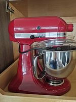 Full view of red KitchenAid Artisan stand mixer with stainless steel bowl and pouring shield
