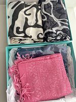 All four scarves folded in two turquoise boxes