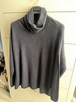 Front view of black cashmere cowl neck sweater on hanger