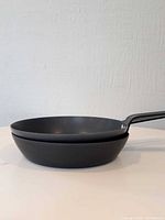 Side view of two stacked Thermalloy fry pans showing non-stick interior and black exterior