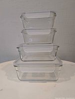 Four stacked glass containers showing graduated sizes and lids