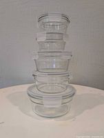 stacked view of five clear glass containers with snap lids