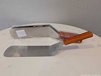 Two of four stainless steel spatulas showing stainless blades and wooden handles still in packaging