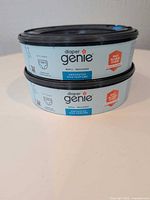 Two stacked Diaper Genie Essentials refill cartridges showing brand and unscented label