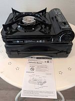 Gas One GS-3700 stove sitting on carry case with manual in foreground