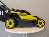 Left side view of Ryobi 13" mower showing wheels, deck, grass bag