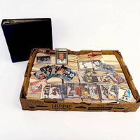 Flat box filled with stacked hockey cards, graded slabs and assorted sleeved cards visible, binder beside
