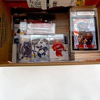 Open box showing stacks of hockey cards with two slabbed Beckett 9.5 cards (Young Guns, Top Shelf Gretzky)