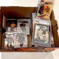 Box of assorted hockey cards with two graded cards visible on top