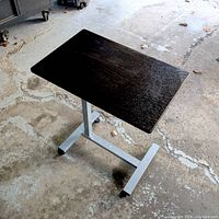 Full view of adjustable laptop table showing top, pedestal, and wheeled base