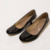 Pair of black patent mid-heel pumps side view