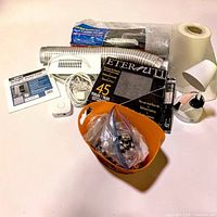 Lot overview showing access panel, vent hoses, Eterniti tiles, plastic roll, powered vent cover, SmartThings button, hardware bag and lamp