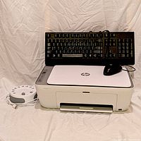 Group shot of HP printer, Lenovo keyboard resting atop, white noise machine and mouse visible
