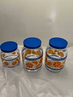 Front view of all three orange motif jars with blue lids
