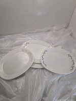 Three oval platters showing two patterned and one plain white