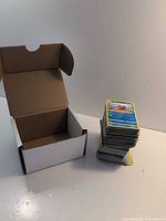 Open empty box next to stack of Pokémon cards