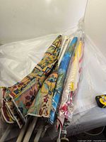 Five folded umbrellas with poles in plastic sleeves