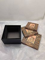 Open black base of largest box with three patterned lids showing tiger design