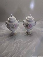 Front view of both matching bone china vases with lids on