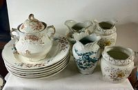Group shot of all 11 pieces: lidded sugar bowl atop stack of six bowls, four assorted vases/pitchers beside