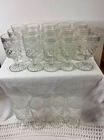 Group of 19 clear pressed glass stemmed goblets displayed on two tiers
