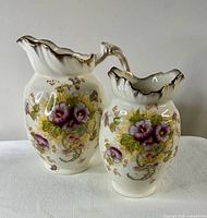 Water pitcher and small vase, frontal view showing floral pattern and gold accents.