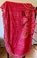 Pink chenille bedspread draped to show overall colour, design and fringe