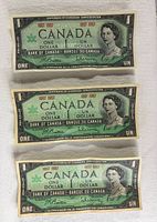 Three 1967 one-dollar banknotes stacked showing overall quantity and wear.