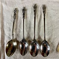 Four EPNS Apostle spoons laid side by side