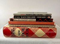 Stack of all six cookbooks showing varied bindings and titles