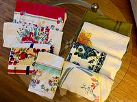 Group of eight folded vintage tablecloths showing variety of prints and colors