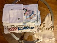 Stack of folded vintage linens showing embroidery, crochet trims and scroll designs