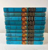Stack of nine blue-spined Hardy Boys books showing volume numbers and titles