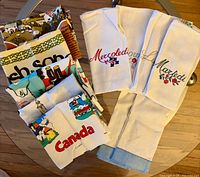 Stack showing printed and embroidered tea towels, partial prints visible