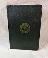 Front cover showing black textured binding and gilt emblem