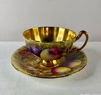 Cup on saucer showing Orchard Fruit motif and full gilt interior