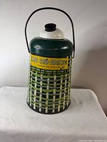 Front view of green basket-weave Cape Cod Cooler with label, lid, spout, and handle visible