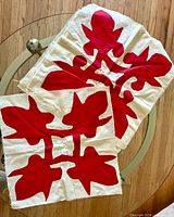 Two quilt squares showing red appliqué on cream cotton