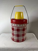 Front view of Columbia Kiltie insulated picnic jug showing tartan print, yellow cup lid, handle