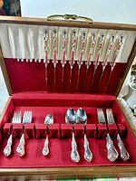 Flatware set arranged in open wooden chest showing all pieces