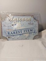Front view of unicorn wall decor sign in plastic wrap