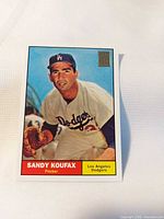 Front view of Sandy Koufax Topps reprint card showing player image, name, team, gold 50th anniversary stamp