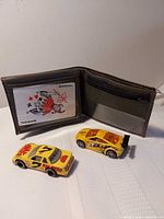 Overview of two diecast cars and open brown wallet